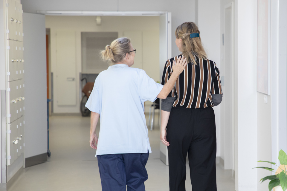 Sygeplejerske og patient går og taler sammen.
