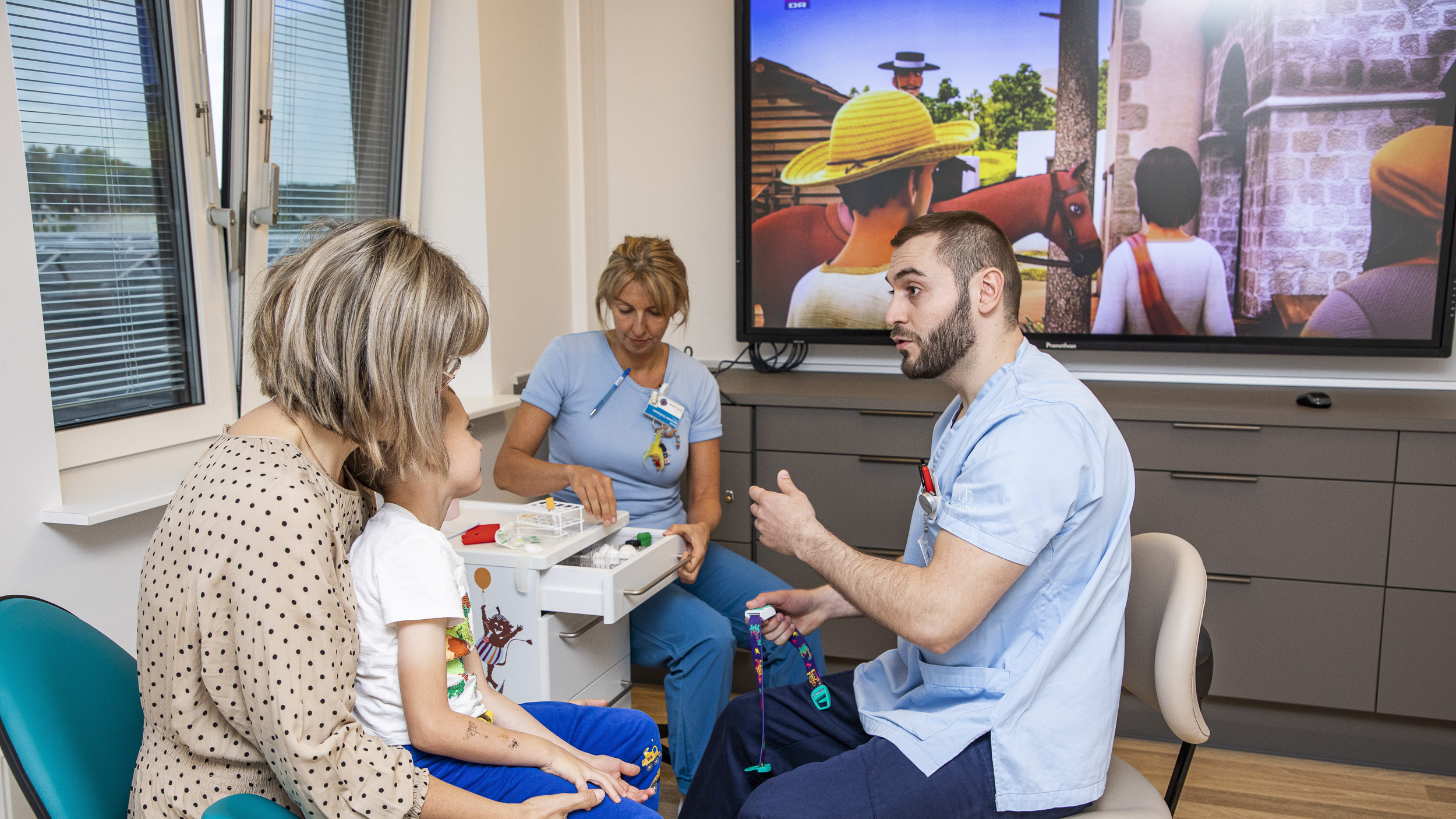 Læge fortæller barn om blodprøver.