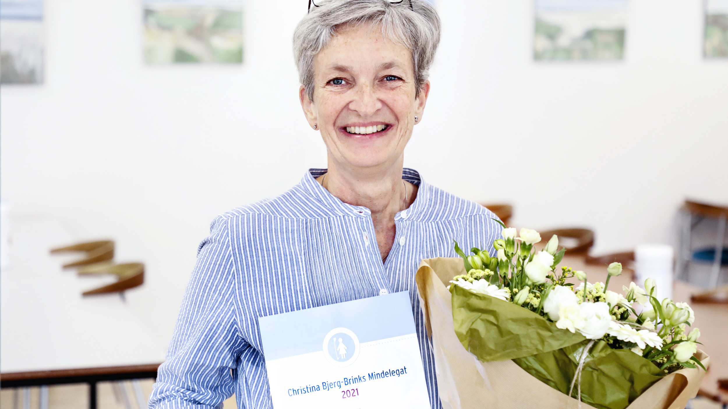 Glad sygeplejerske med blomster og diplom