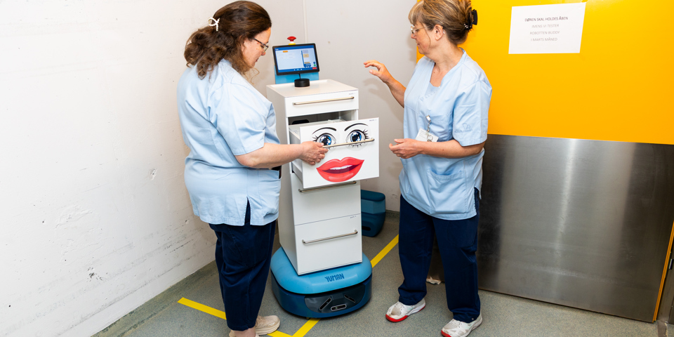  To medarbejdere trykker på skærm på robot