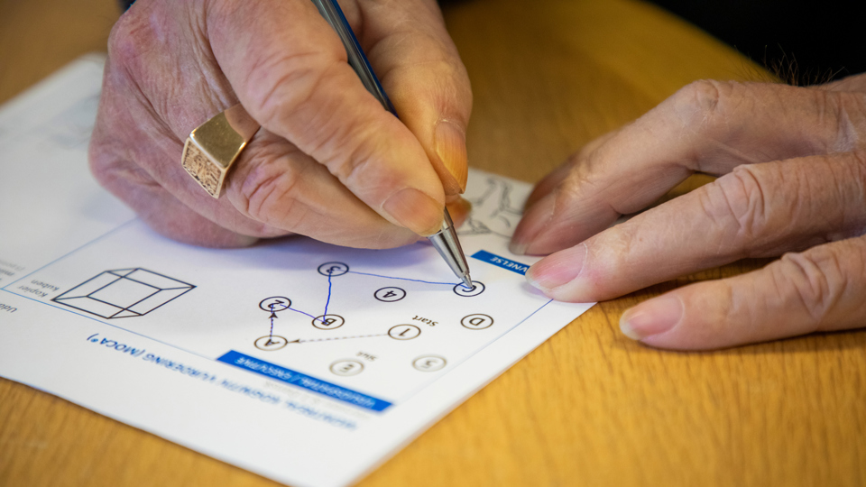 Mand løser opgave på papir med en kuglepen.