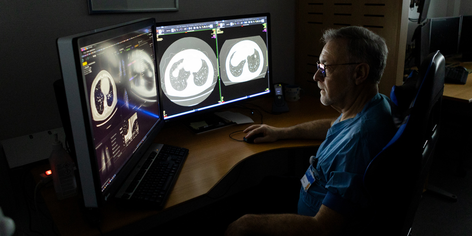 Radiolog sidder ved skærm