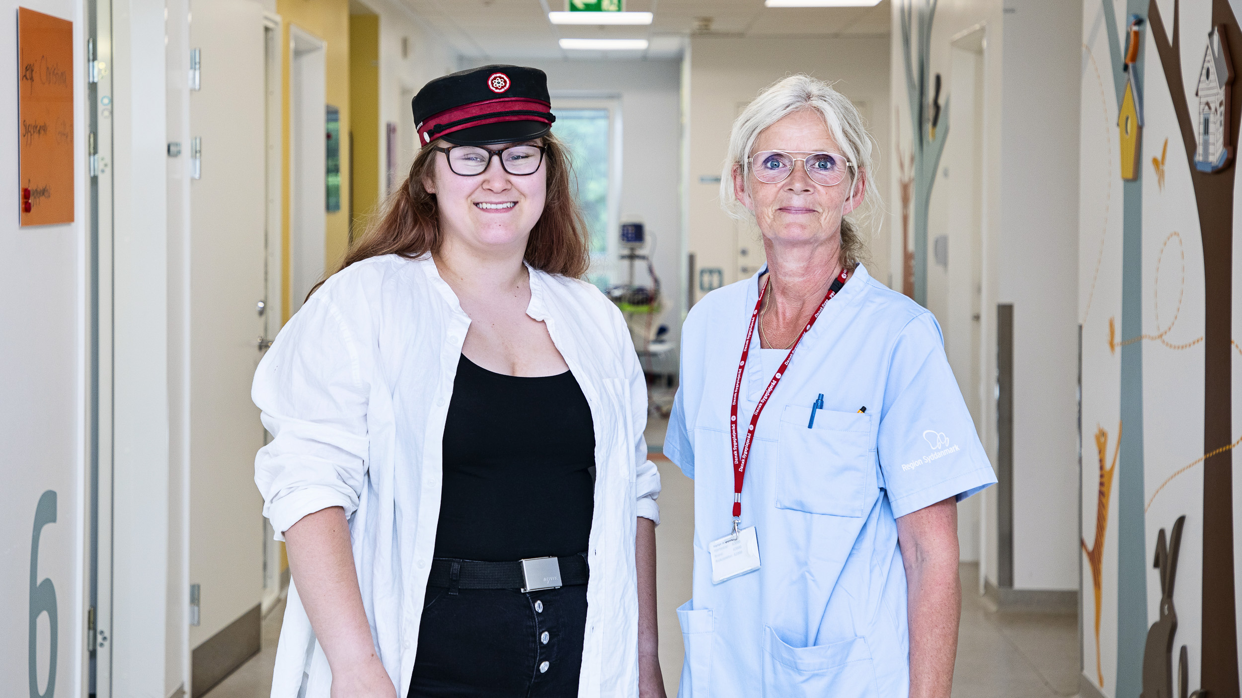 Patient og sygeplejerske står sammen på gangen.