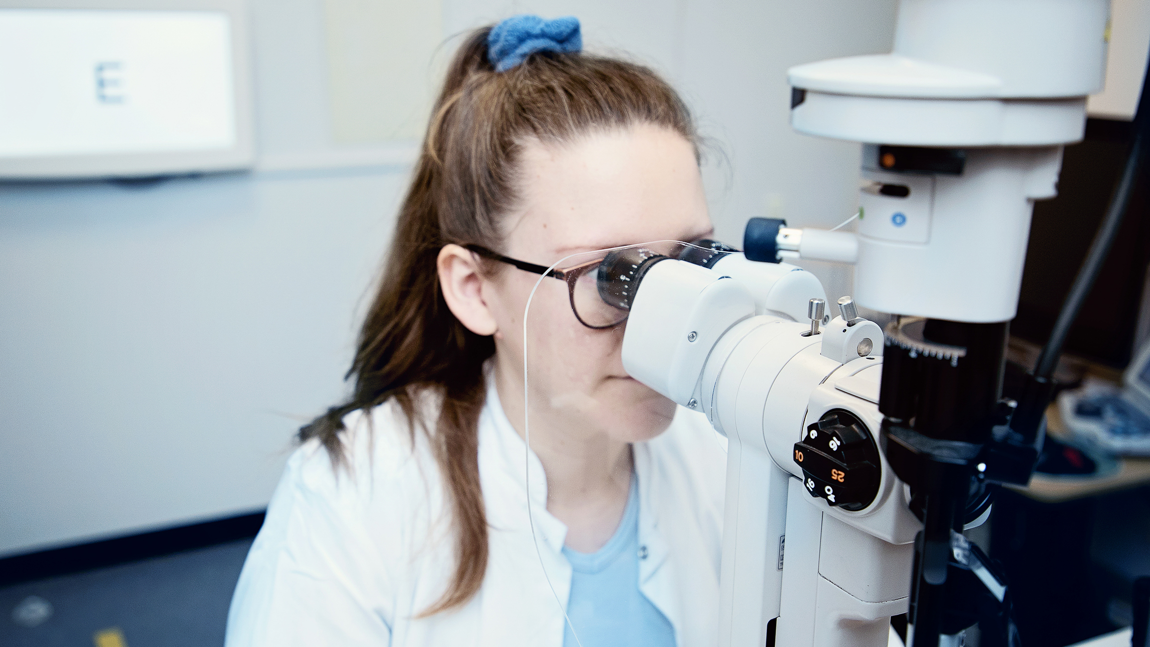 Læge kigger i mikroskop.