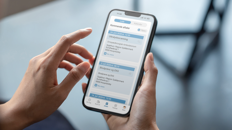To hænder holder mobiltelefon, der viser skærmbillede af ny app